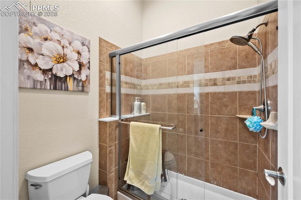 Image 17 of 35: Primary bathroom with tile shower with built-in shelf and upgraded shower h