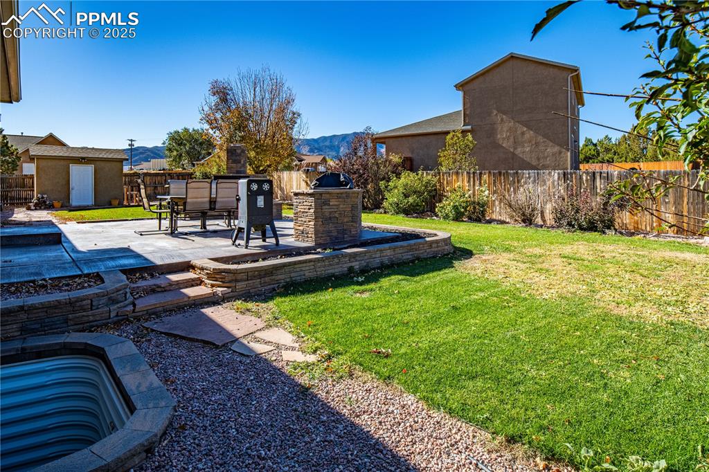Image 30 of 35: Fully Fenced Backyard with Mountain Views and Stained Concrete Patio, Grill