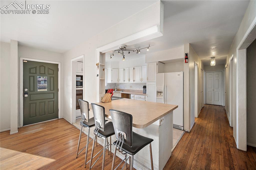 Image 2 of 31: Kitchen featuring white cabinets, white refrigerator, light wood flooring, 