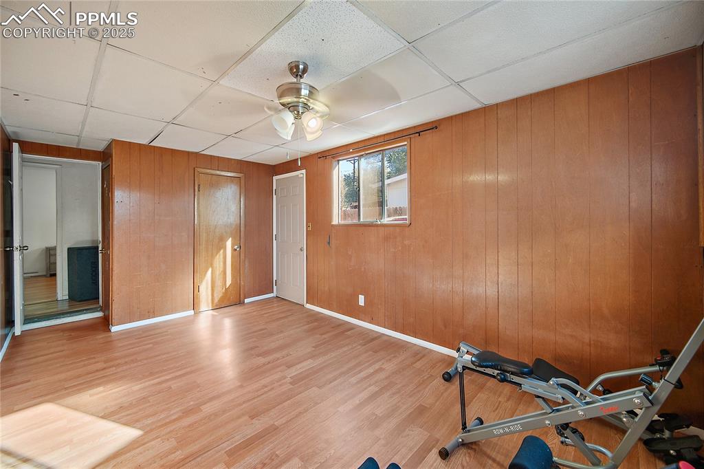 Image 22 of 31: Workout room with wood walls, a paneled ceiling, wood finished floors, and 