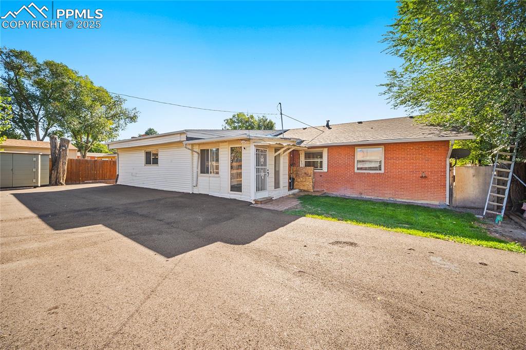 Image 23 of 31: Rear view of house featuring brick siding and roof with shingles
