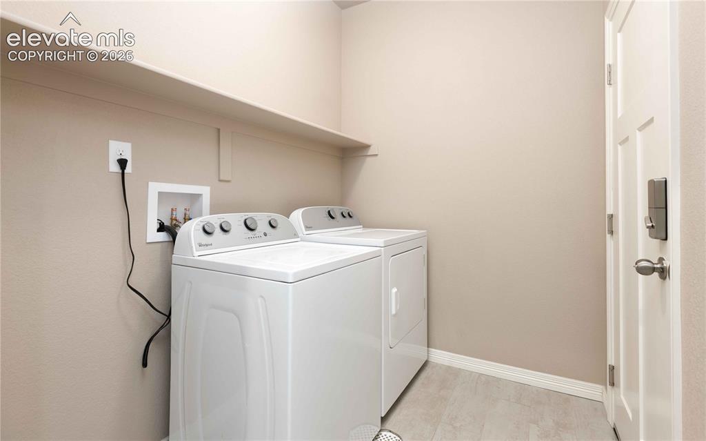 Image 24 of 40: Laundry with built in shelf. Washer and dryer convery, room connects house
