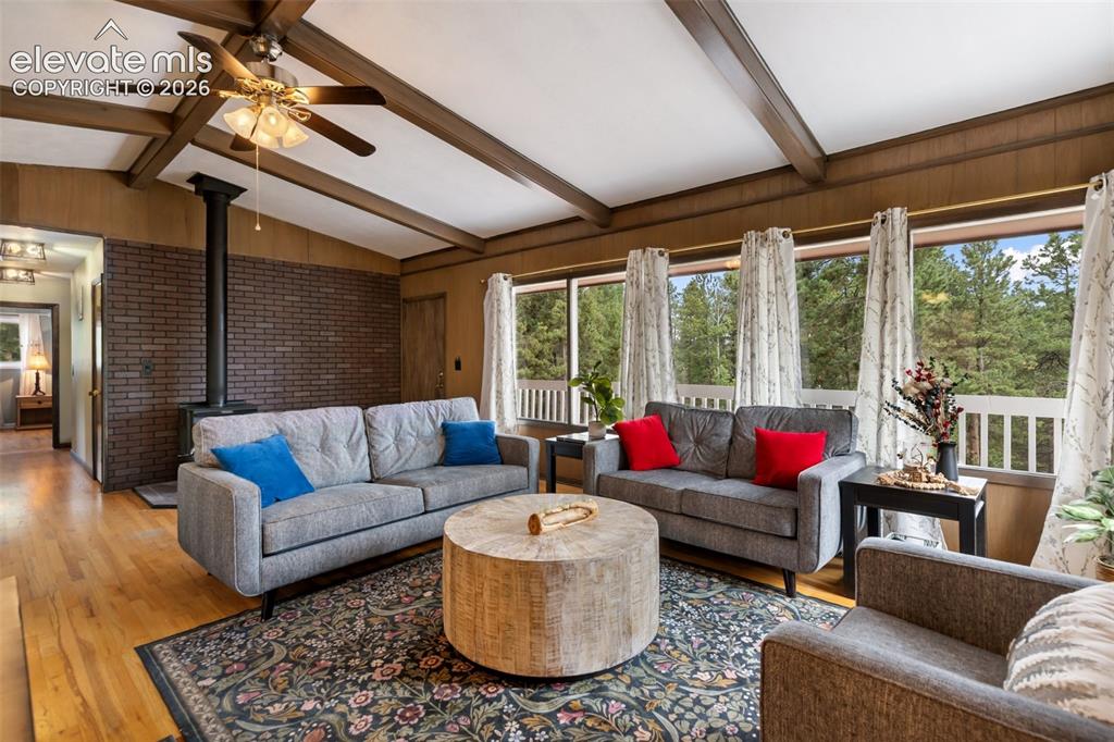Image 5 of 32: Living room with wood stove and beautiful windows and views!