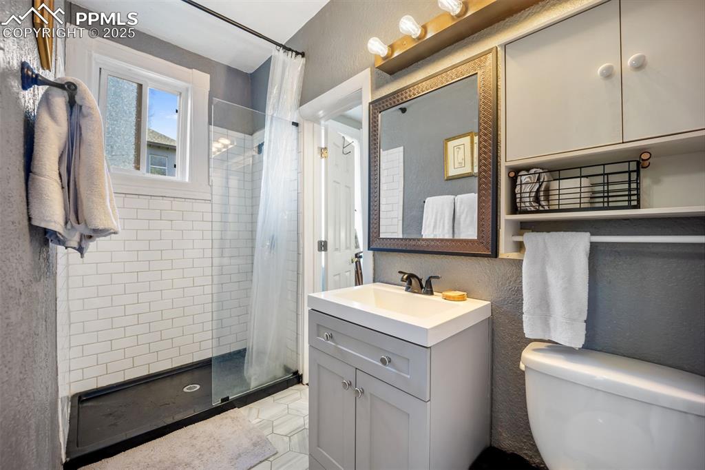 Image 11 of 41: Full bath with a stall shower, vanity, and a textured wall