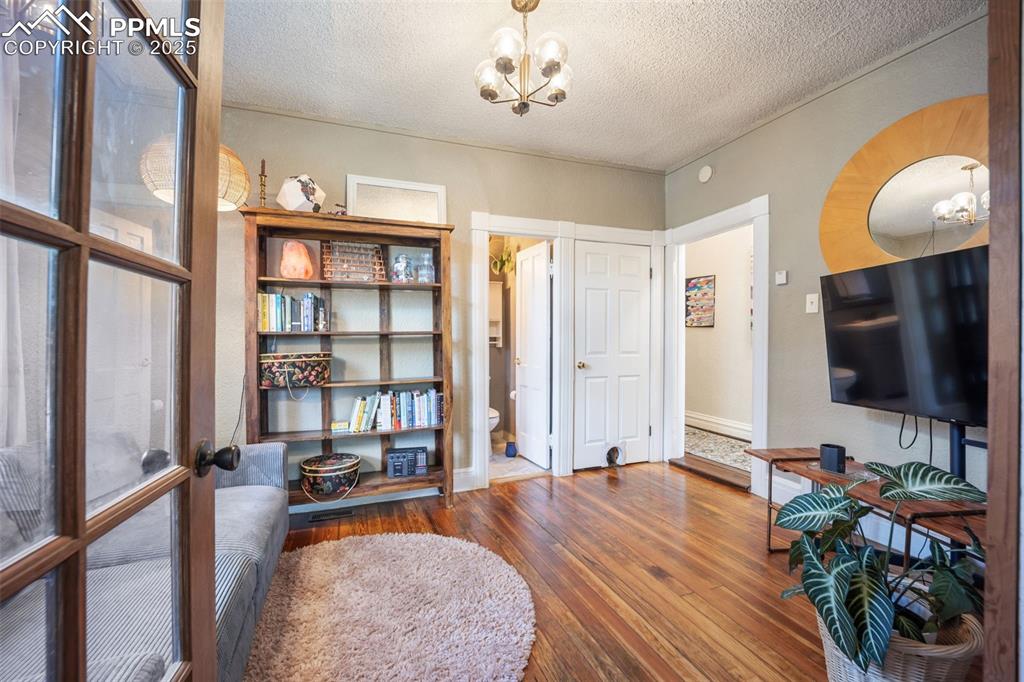 Image 13 of 41: Sitting room with a textured ceiling, a chandelier, and hardwood / wood-sty