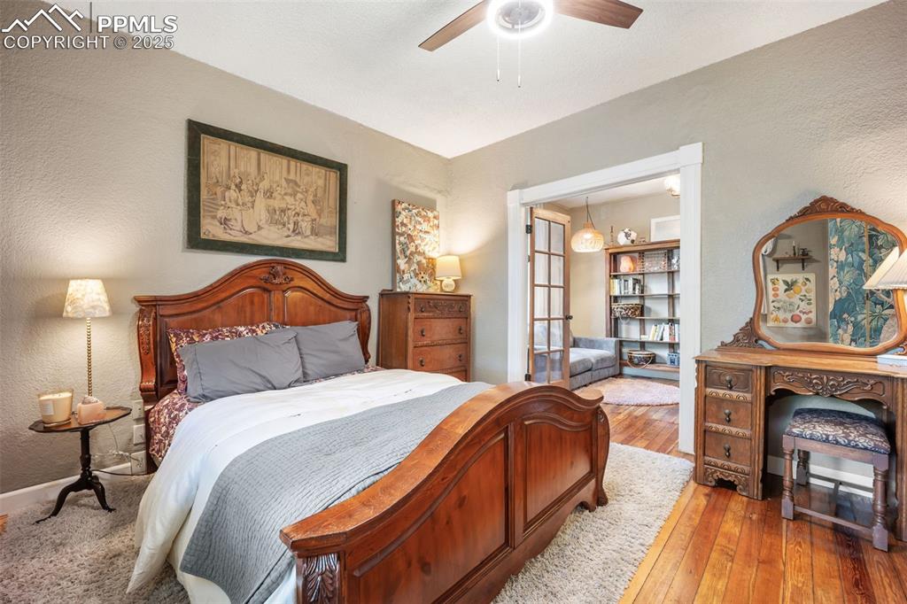 Image 14 of 41: Bedroom featuring a textured wall, wood-type flooring, and a ceiling fan