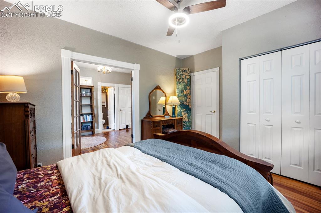 Image 15 of 41: Bedroom featuring wood finished floors, a textured wall, a chandelier, a ce