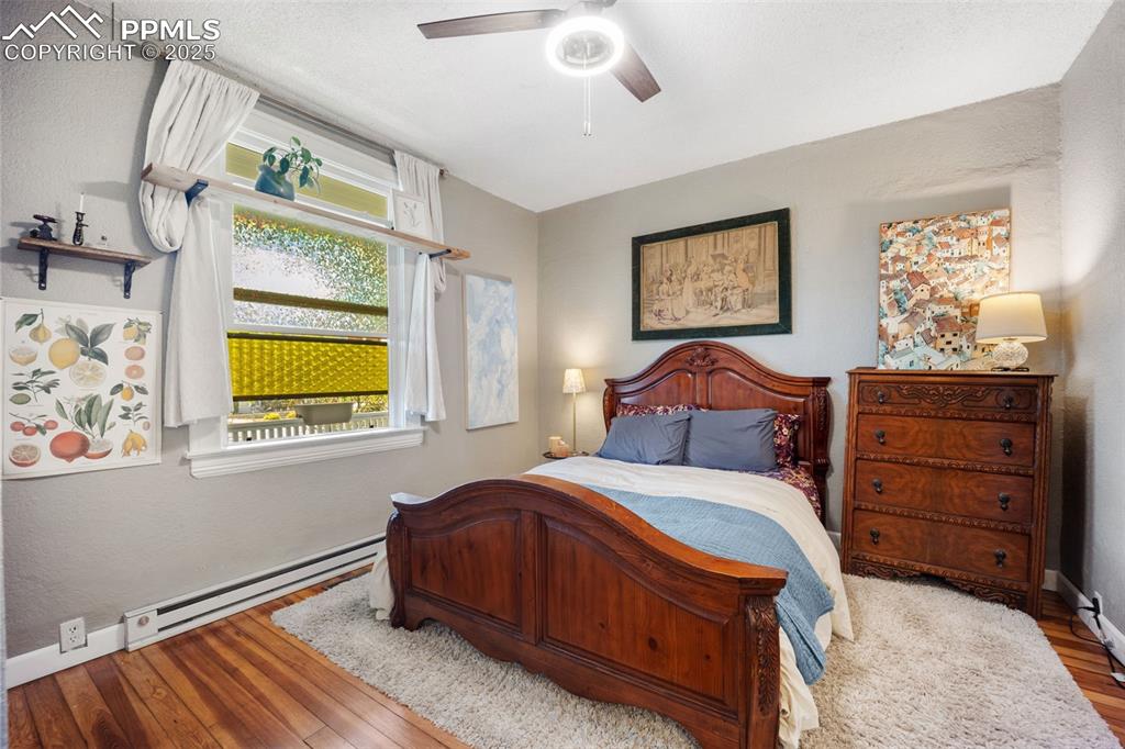 Image 16 of 41: Bedroom with baseboard heating, hardwood / wood-style floors, a textured wa