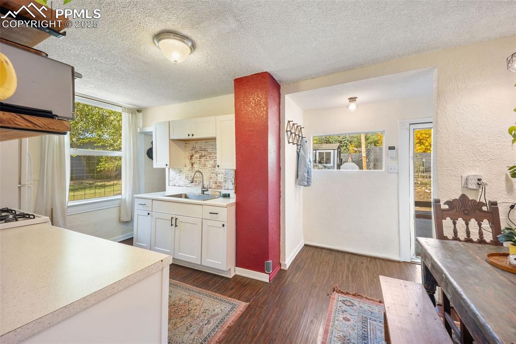 Image 17 of 41: Kitchen featuring a textured wall, white cabinets, light countertops, dark
