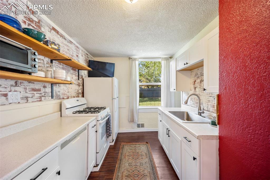 Image 18 of 41: Kitchen with open shelves, white cabinetry, white appliances, dark wood-sty