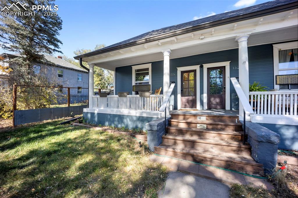 Image 2 of 41: Doorway to property with a porch and a yard