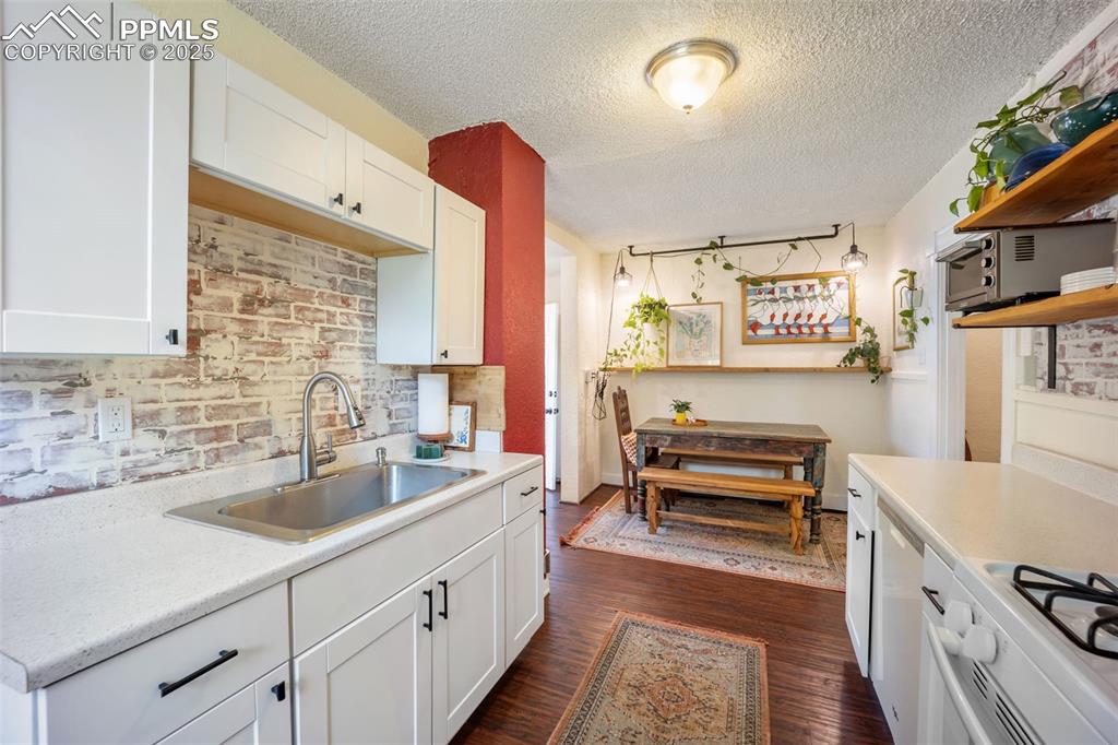 Image 20 of 41: Kitchen with light countertops, dark wood finished floors, white cabinets,