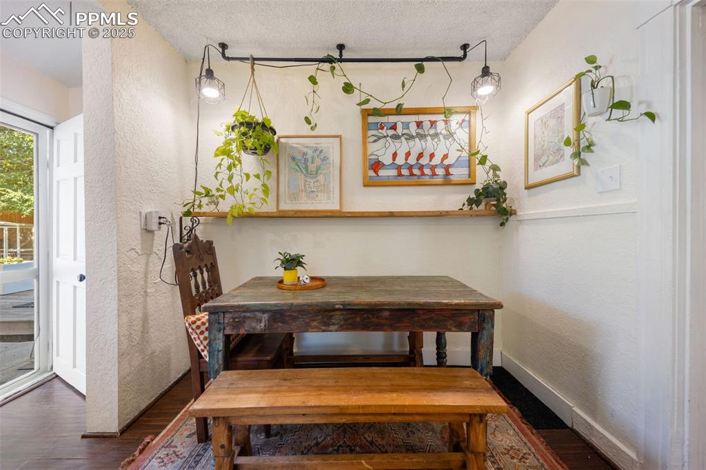 Image 22 of 41: Dining area featuring a textured wall, dark wood-type flooring, and a textu