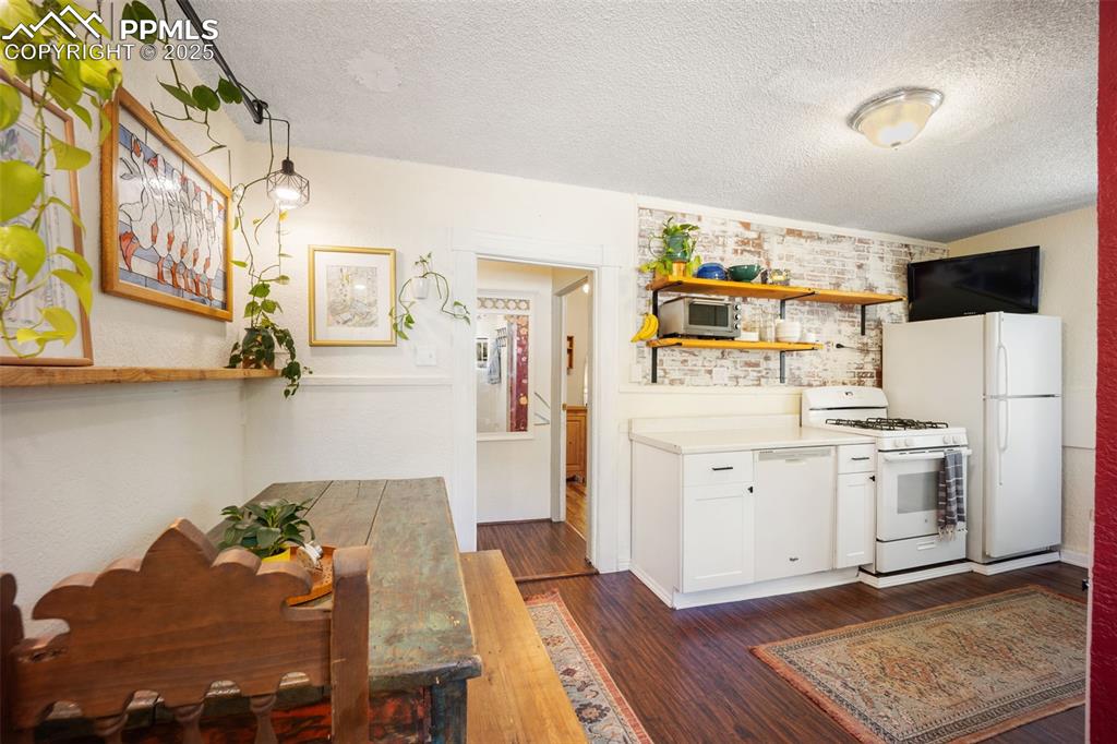 Image 25 of 41: Kitchen featuring open shelves, a textured ceiling, dark wood-type flooring