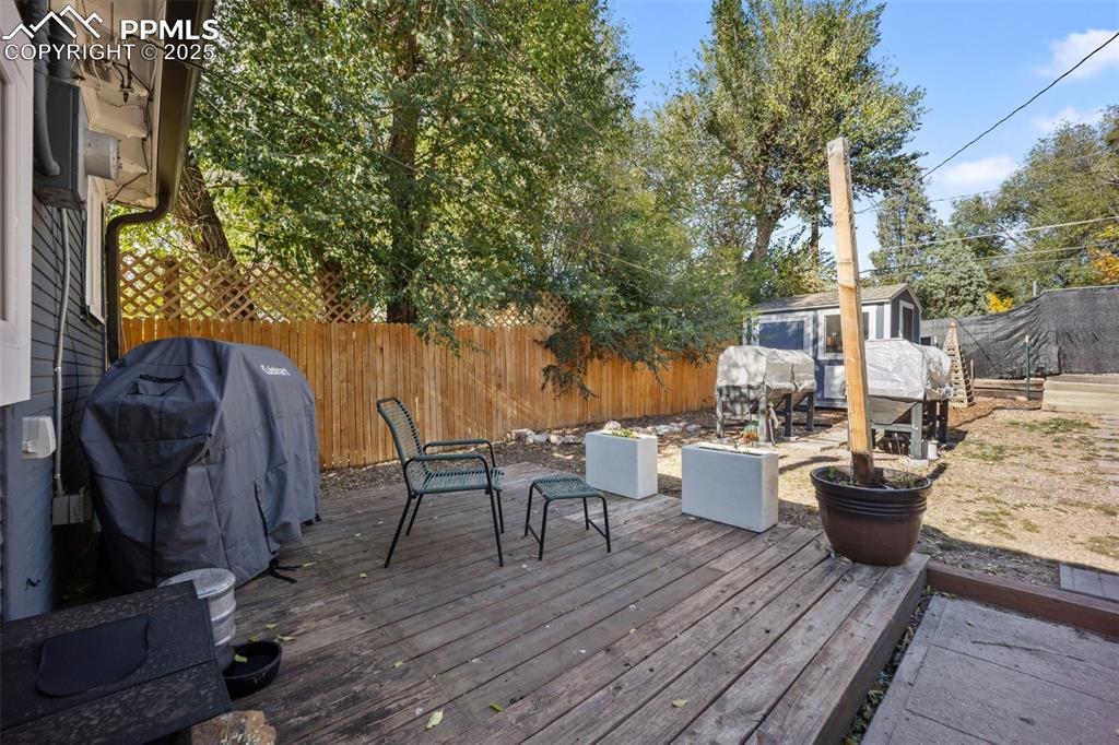Image 26 of 41: Wooden terrace with a fenced backyard, area for grilling, and a shed