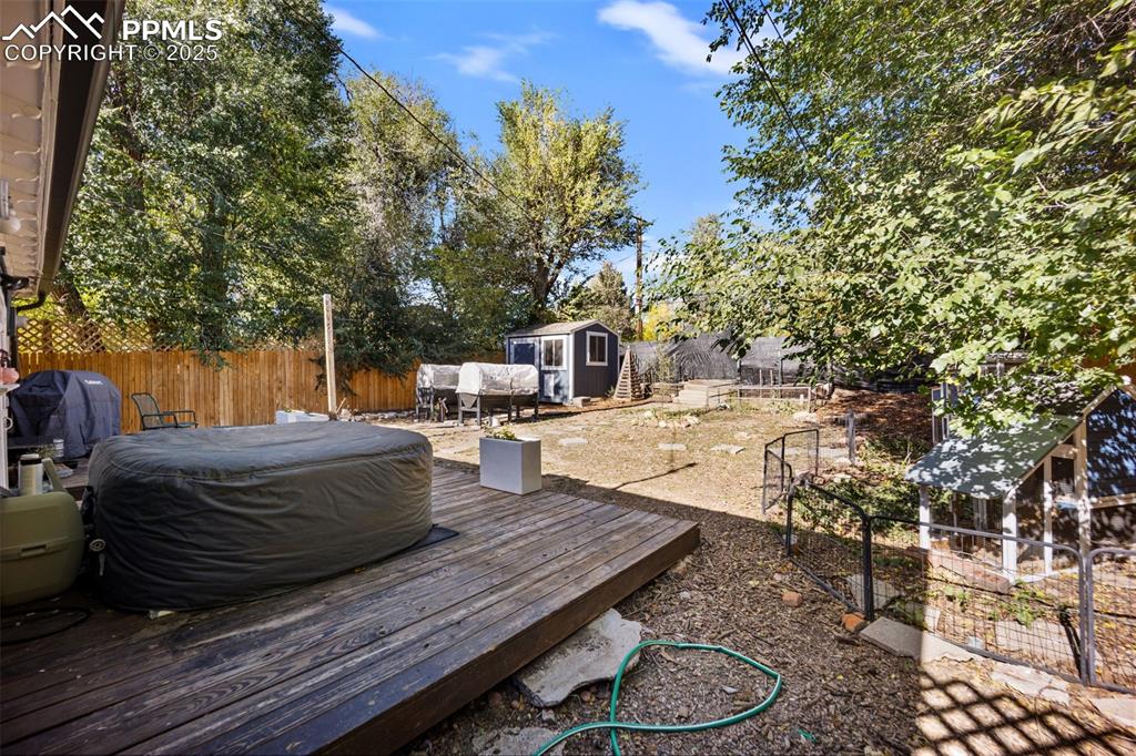 Image 34 of 41: Wooden terrace with a fenced backyard, a grill, and a storage unit