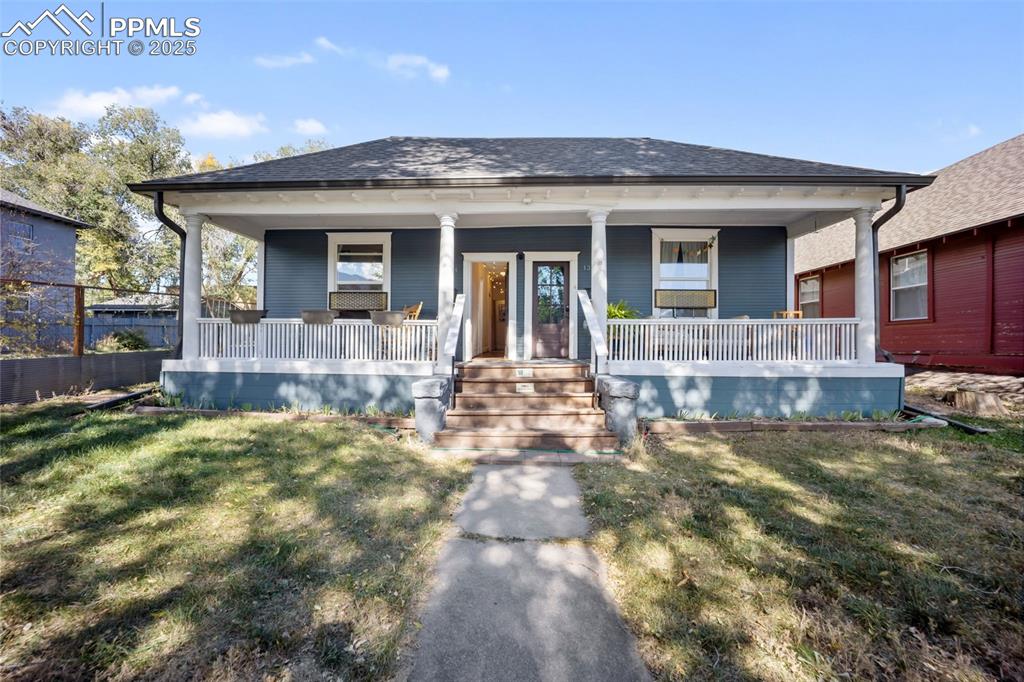 Image 7 of 41: Bungalow-style house featuring a porch, a front lawn, and roof with shingle