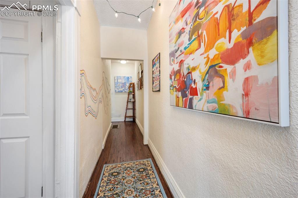 Image 8 of 41: Corridor featuring dark wood-style floors, a textured wall, and a textured
