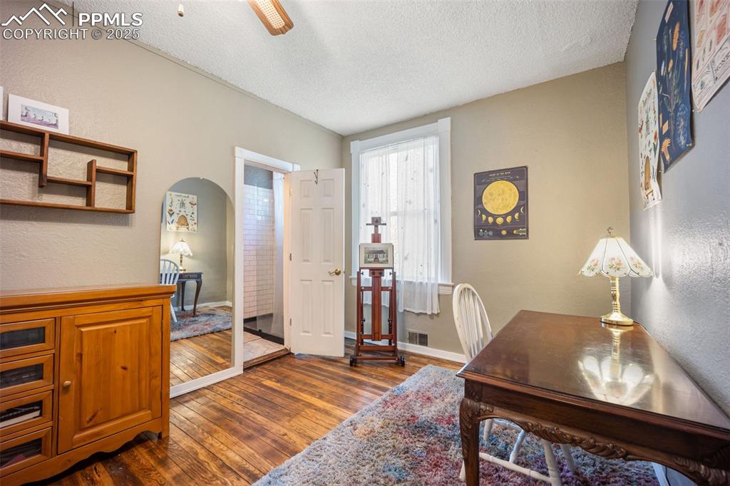 Image 9 of 41: Home office with a textured wall, dark wood finished floors, a textured cei