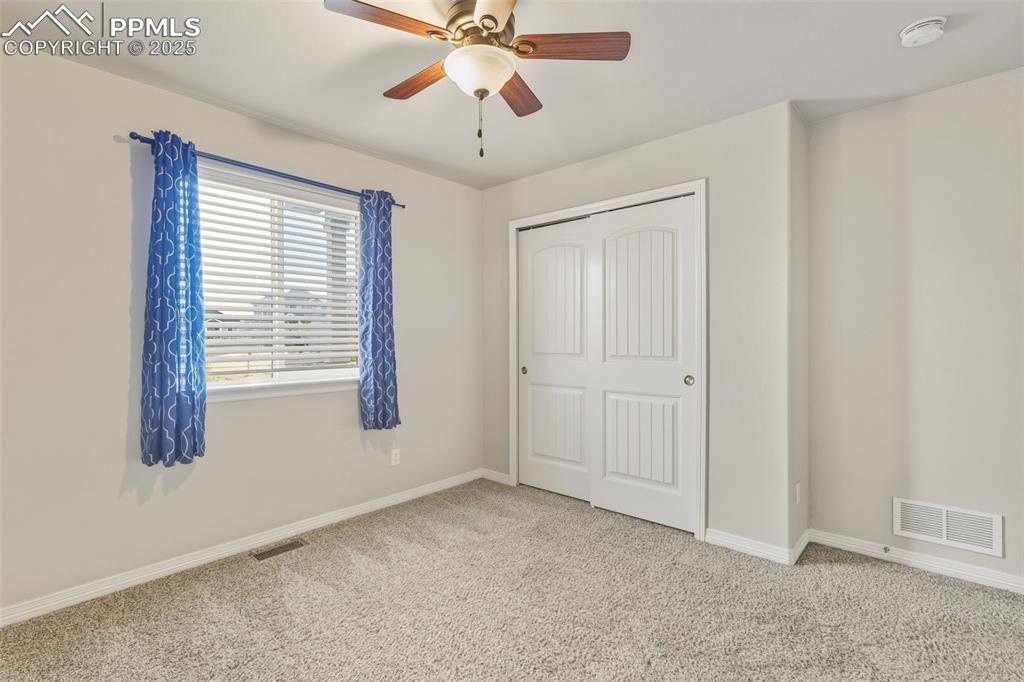Image 13 of 27: Unfurnished bedroom with carpet flooring, a closet, and a ceiling fan