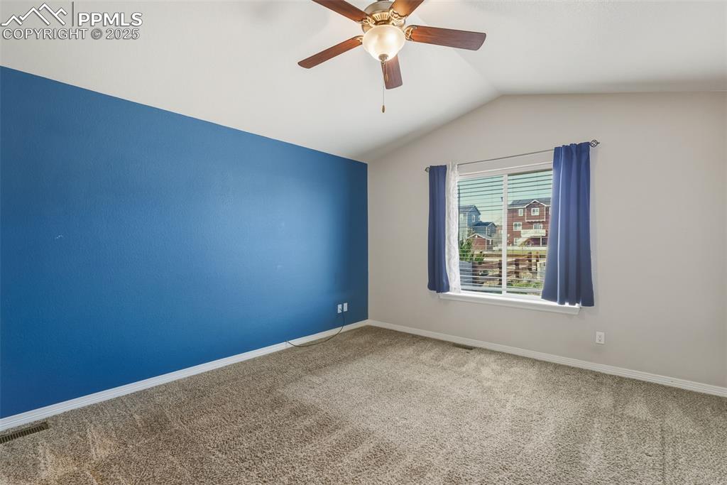 Image 14 of 27: Empty room with carpet flooring, vaulted ceiling, and a ceiling fan