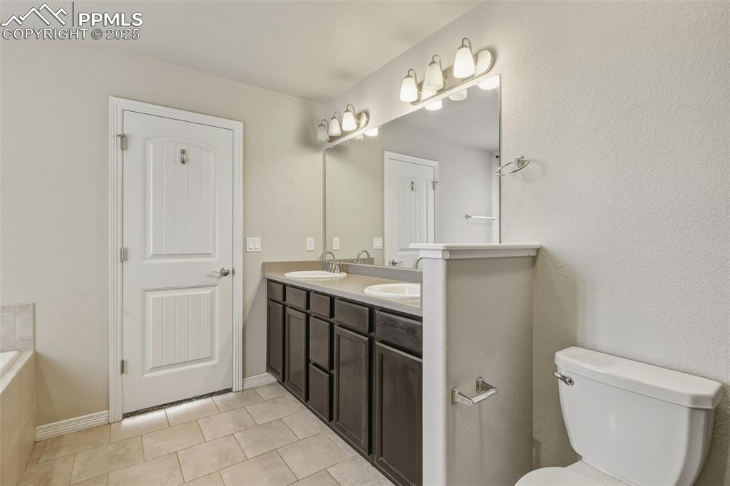 Image 15 of 27: Bathroom with double vanity, a bathtub, and light tile patterned floors
