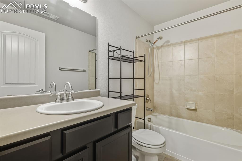 Image 24 of 27: Full bath with shower / bath combination, vanity, and light tile patterned 