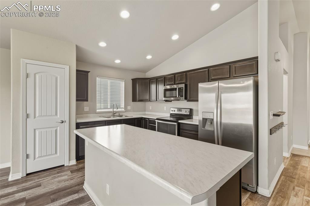 Image 7 of 27: Kitchen with lofted ceiling, stainless steel appliances, dark brown cabinet