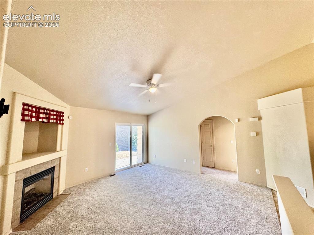 Image 11 of 39: Spacious living area featuring vaulted ceilings, a tiled fireplace with bui
