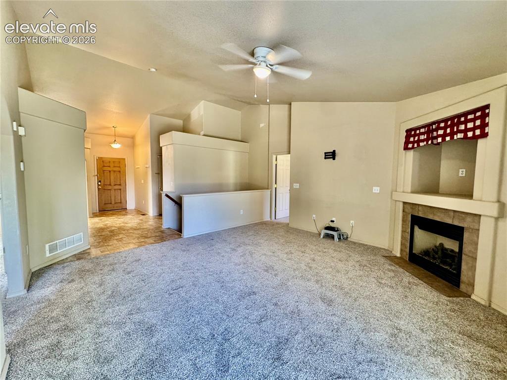 Image 12 of 39: Carpeted living area featuring a built-in fireplace with a tile surround an