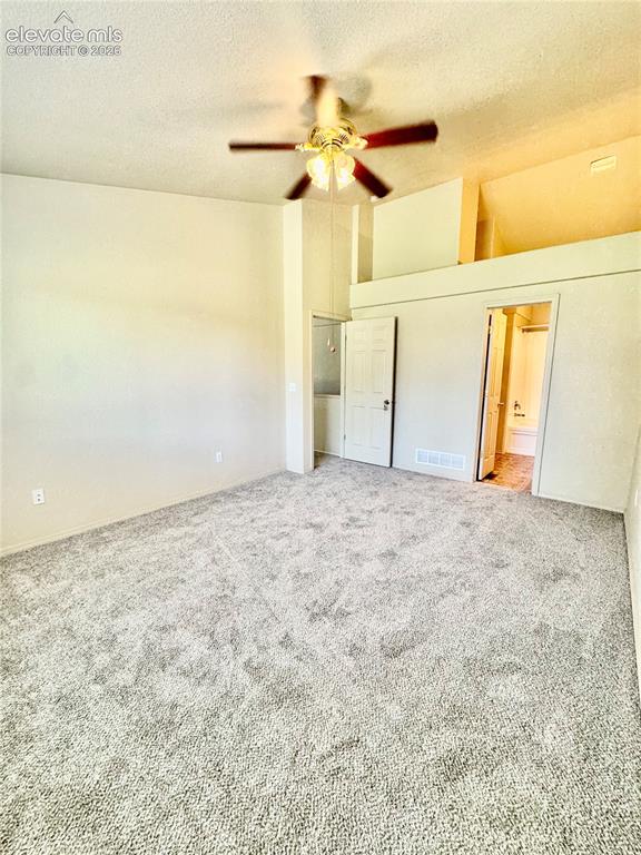 Image 15 of 39: Carpeted interior space featuring a ceiling fan, vaulted ceilings, and a li