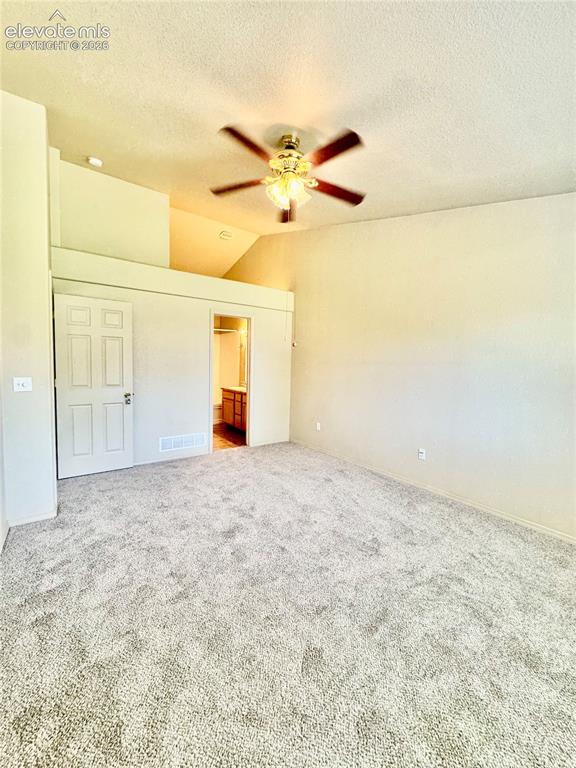 Image 16 of 39: Carpeted interior room featuring a ceiling fan, vaulted ceiling, and neutra