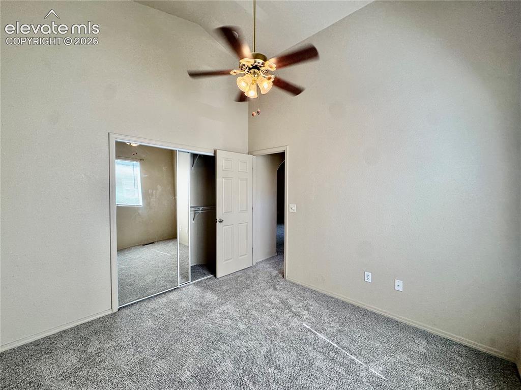 Image 17 of 39: Vaulted ceiling bedroom featuring plush gray carpet, a ceiling fan with int