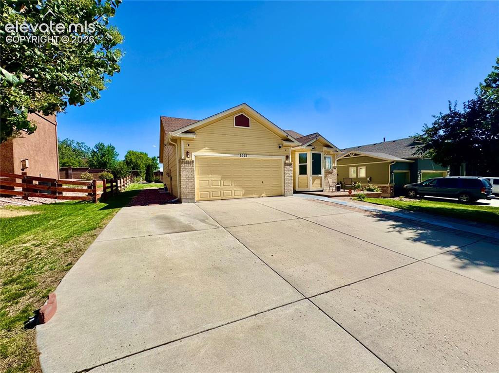 Image 2 of 39: Yellow-sided residence featuring an attached garage and stone accents