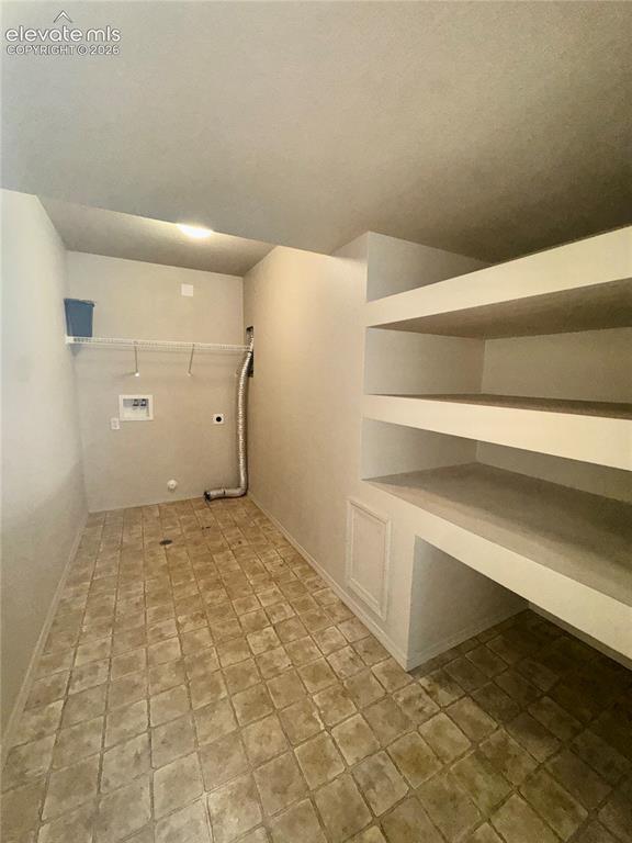 Image 27 of 39: Utility room featuring built-in shelving, a wire rack, and a patterned tile