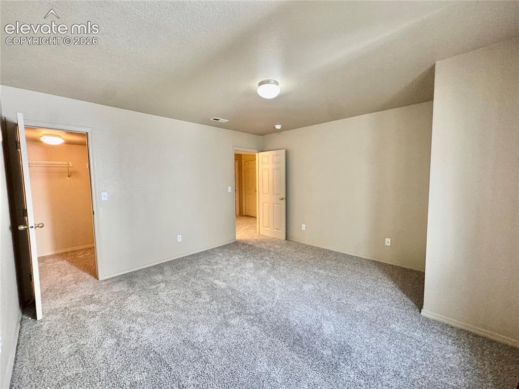 Image 31 of 39: Spacious room featuring neutral-toned walls and plush gray carpeting