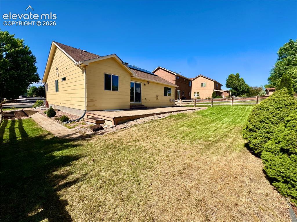 Image 34 of 39: Spacious backyard featuring a wooden deck, sliding glass doors, a split rai