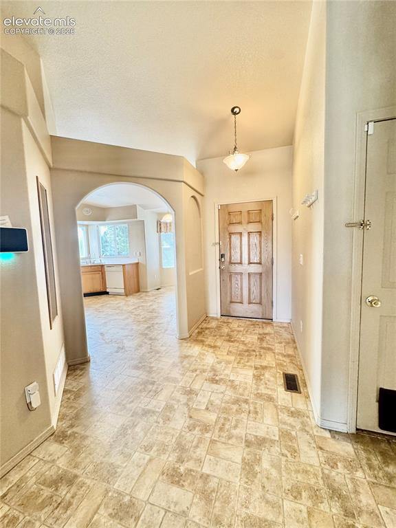 Image 5 of 39: Entryway featuring a wood-panel front door, pendant lighting, textured viny