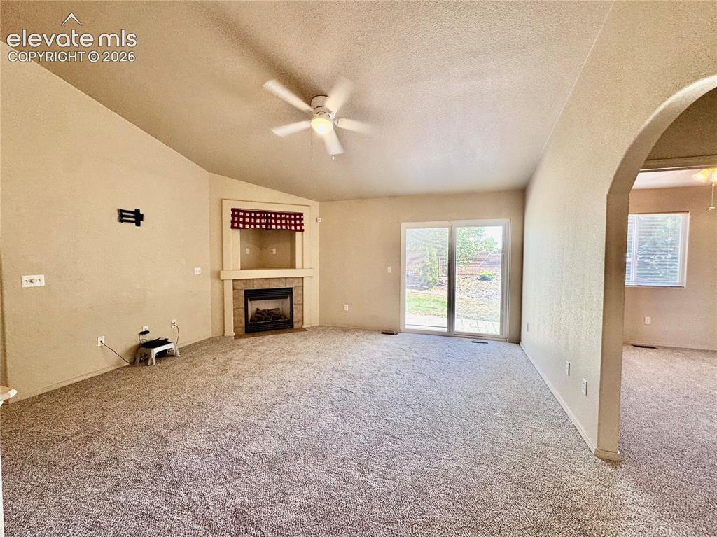 Image 9 of 39: Spacious living area featuring vaulted ceilings, a ceiling fan, and plush c