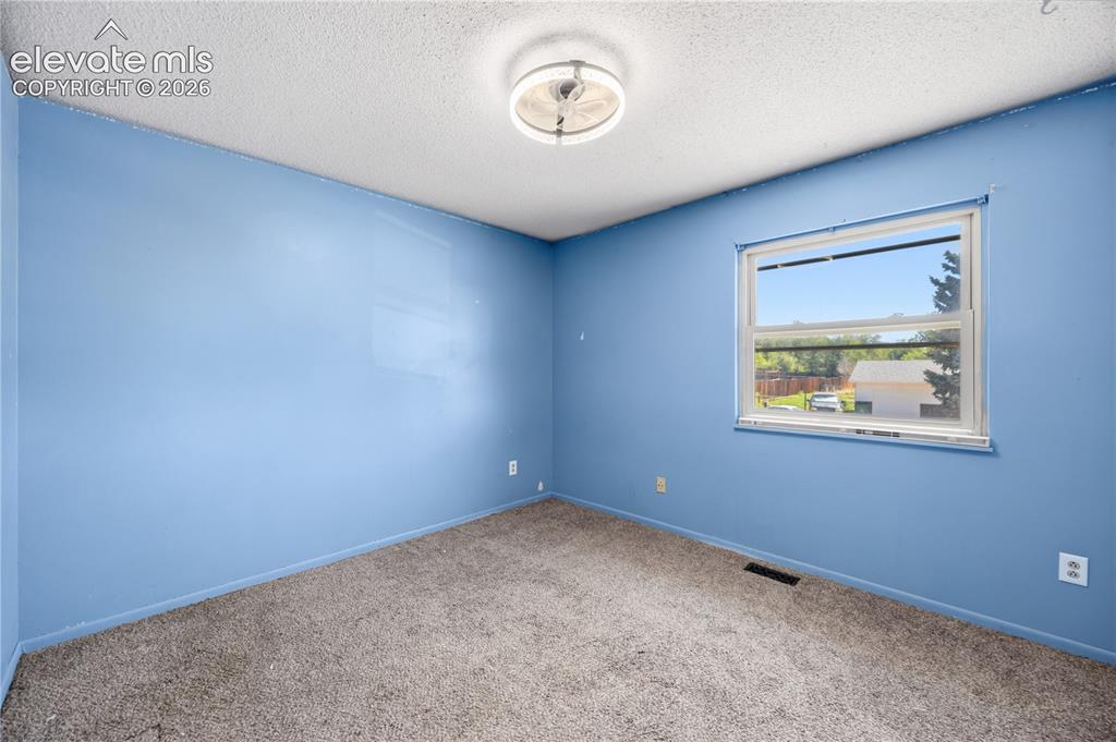 Image 18 of 35: Carpeted room with a single window and ceiling-mounted light fixture
