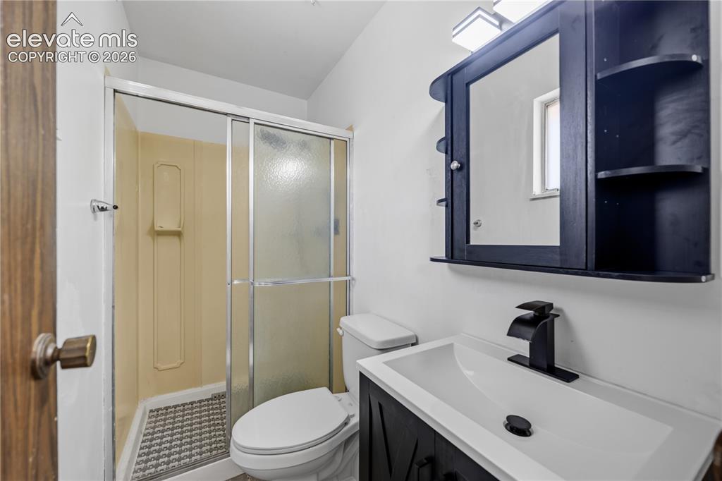 Image 24 of 35: Shower with sliding glass doors, built-in vanity with integrated sink, blac