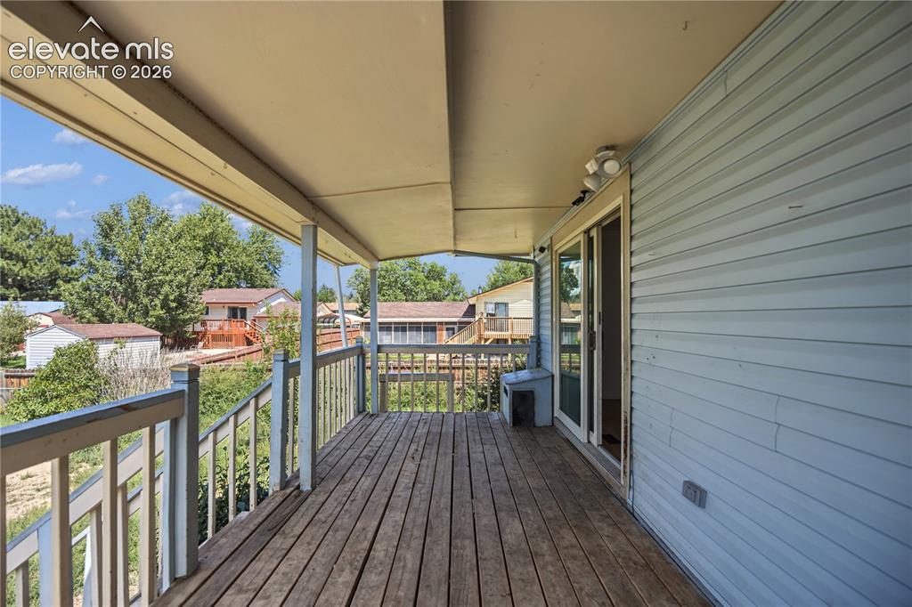 Image 32 of 35: Covered wood deck with slatted railing and exterior siding