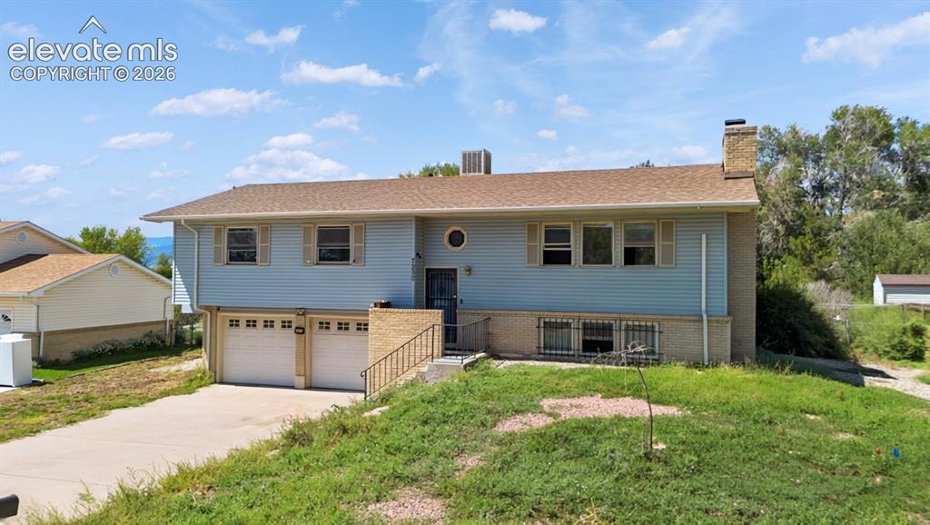 Image 5 of 35: Split-level residence featuring light blue siding, a two-car garage, a conc