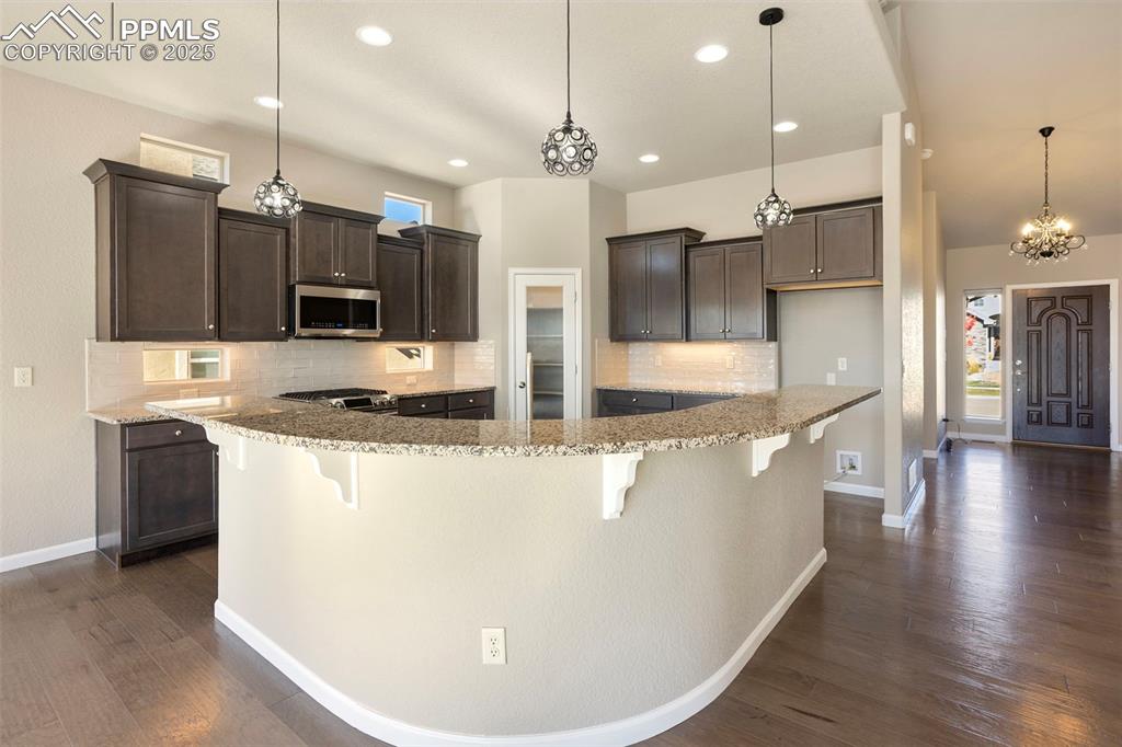Image 13 of 48: Kitchen with backsplash, a chandelier, pendant lighting, appliances with st