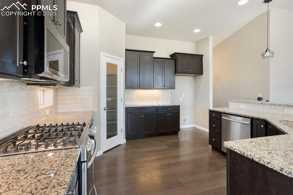 Image 15 of 48: Kitchen featuring appliances with stainless steel finishes, decorative back