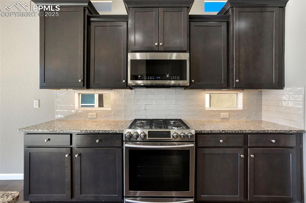 Image 16 of 48: Kitchen featuring stainless steel appliances, light stone countertops, a te
