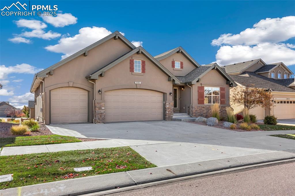 Image 2 of 48: Traditional-style house featuring stucco siding, concrete driveway, stone s
