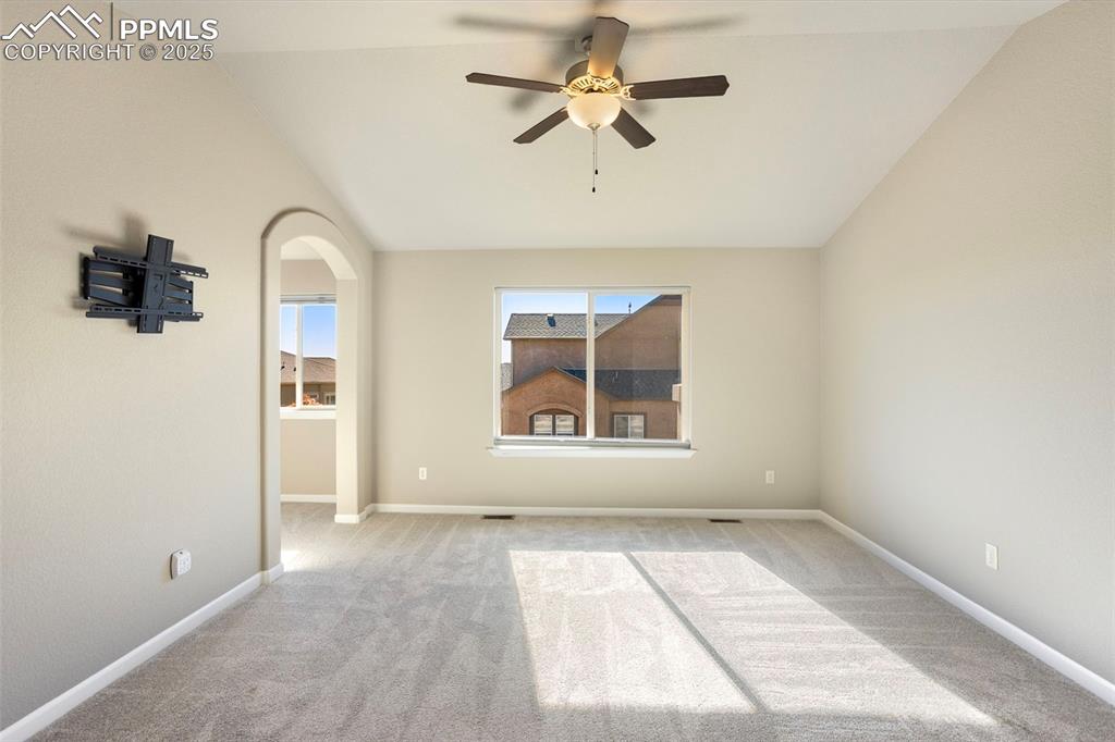 Image 20 of 48: Unfurnished room featuring lofted ceiling, light colored carpet, arched wal