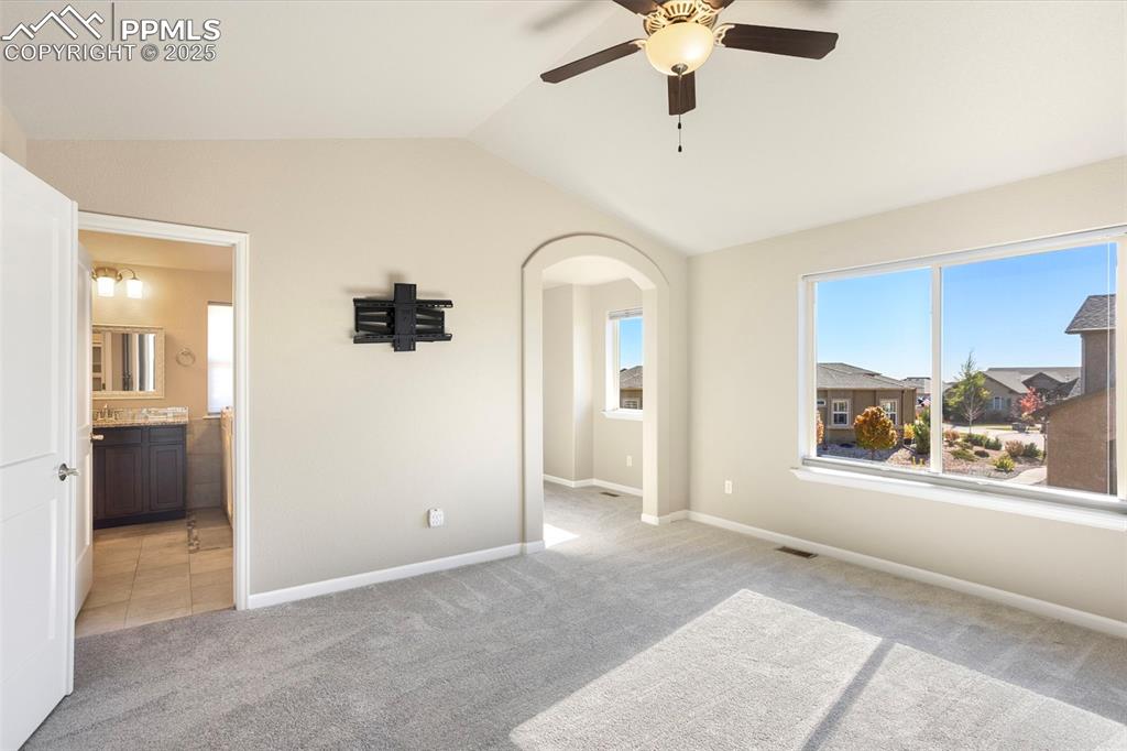 Image 21 of 48: Unfurnished bedroom featuring light carpet, vaulted ceiling, arched walkway