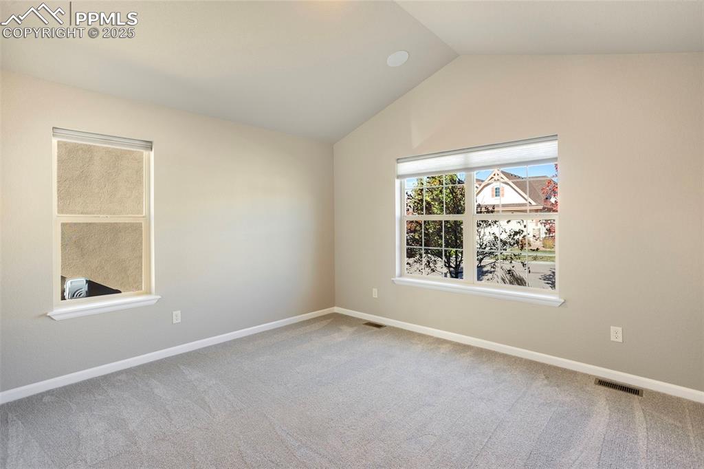 Image 22 of 48: Empty room with light carpet and vaulted ceiling